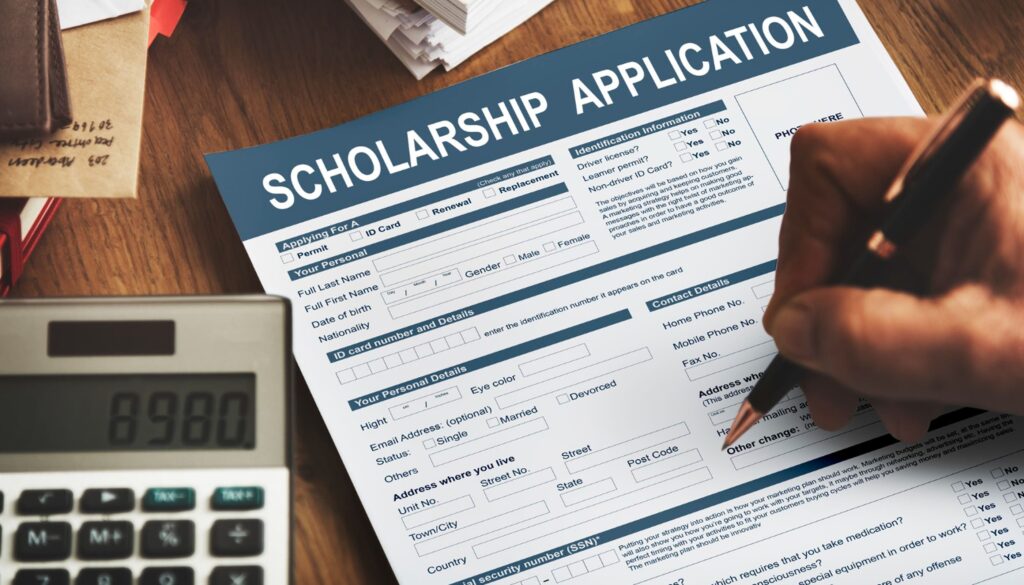 Student filling out a scholarship application form with a pen on a desk, alongside a calculator, wallet, and documents, symbolizing financial aid, education funding, and college admission support.